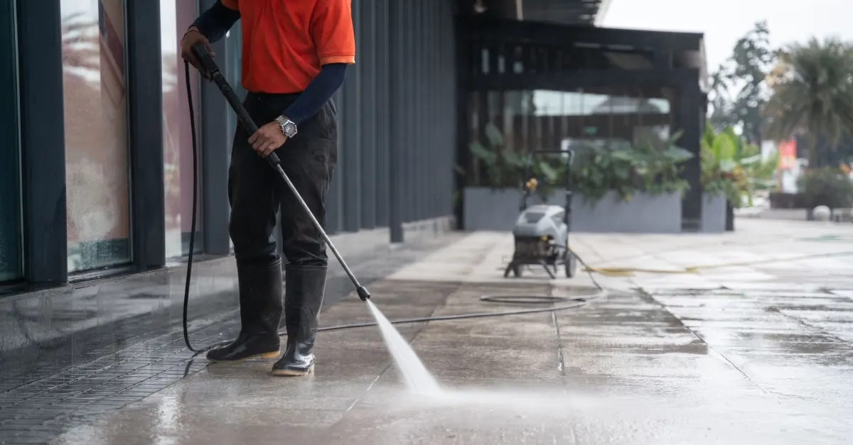 Pressure washing a walkway near a building entrance